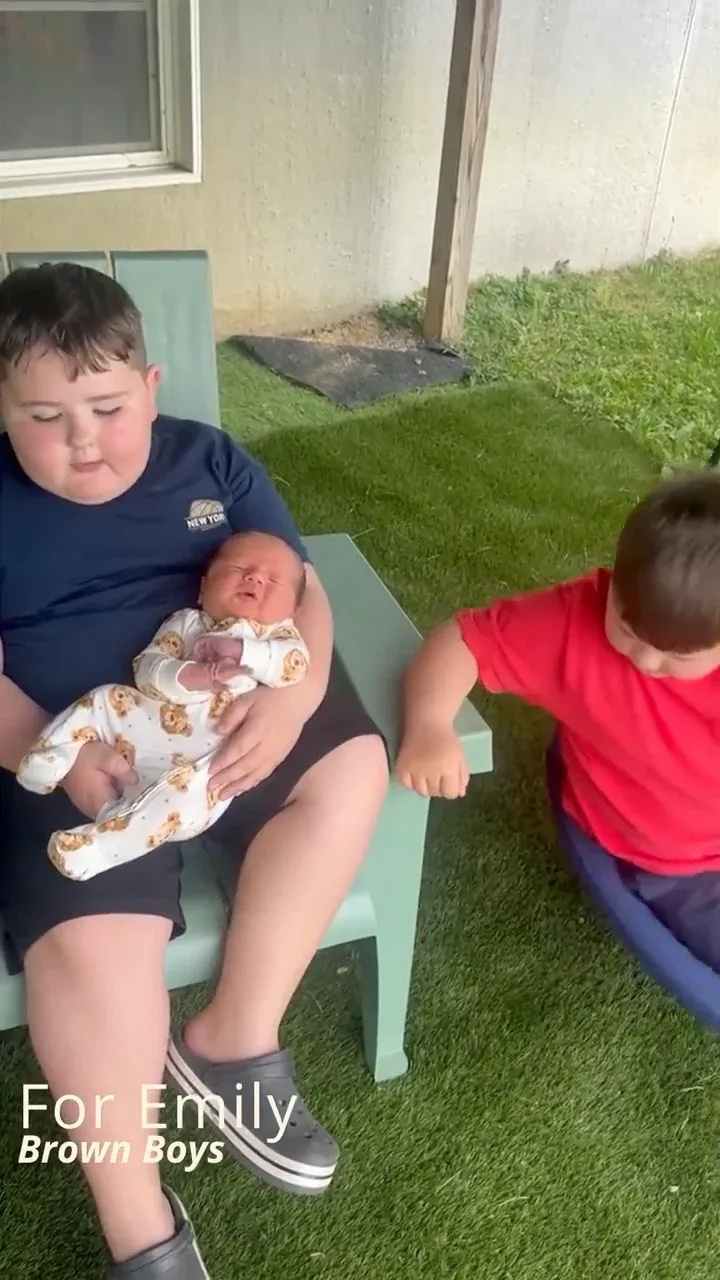 The Brown boys holding a newborn baby in a video for Emily